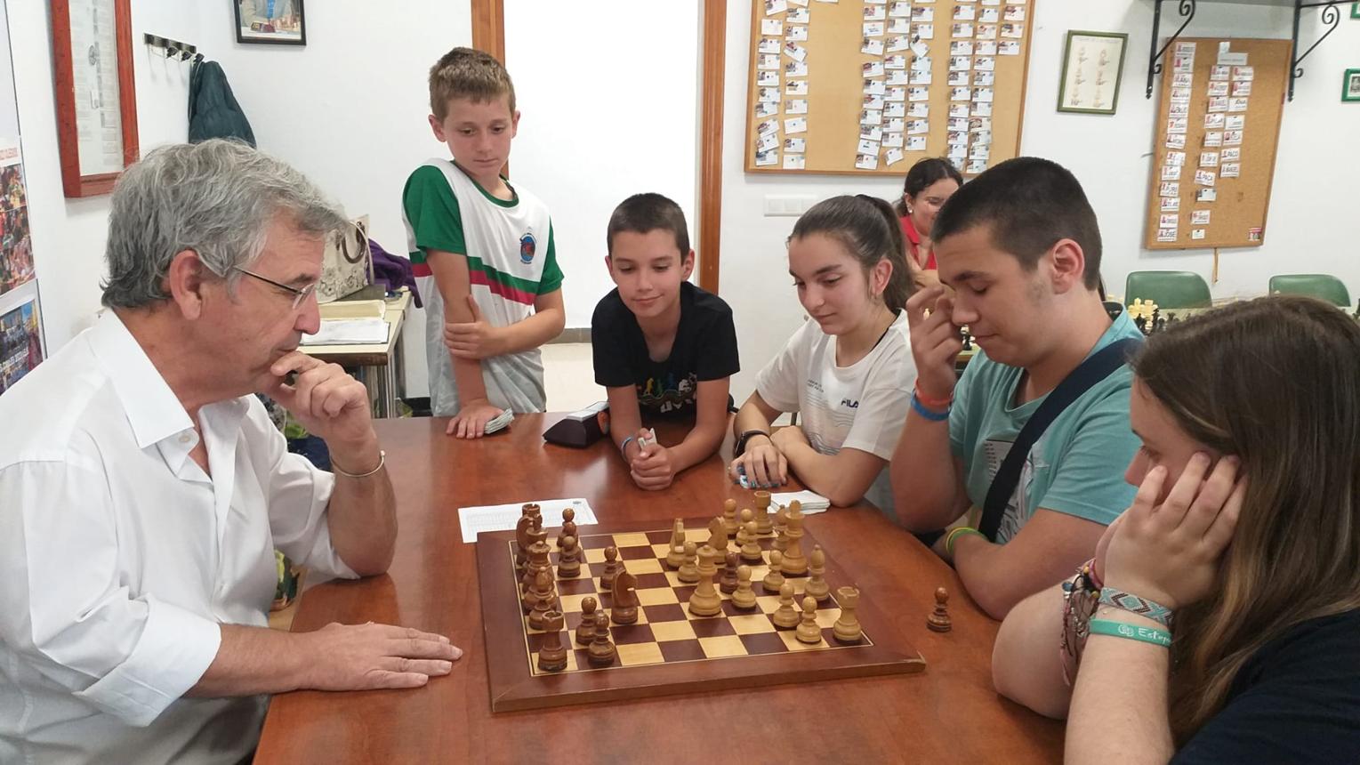 Professeur d'échecs expliquant une position à des collégiens
